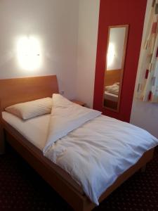 a bedroom with a white bed with a mirror at Gasthof Zur Post in Bad Goisern