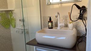 a bathroom with a sink and a glass shower at Suíte elegante Caxambu in Caxambu