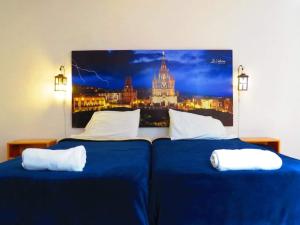 two beds in a room with a picture on the wall at La Catrina Hostel in San Miguel de Allende