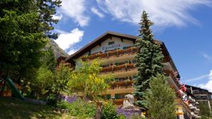 ein Hotel in den Bergen mit einem Baum in der Unterkunft Alpenblick Superior in Zermatt