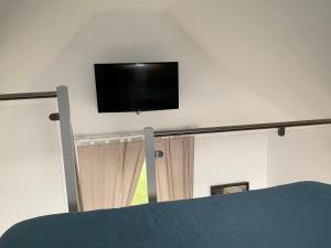 TV de pantalla plana en una pared sobre una mesa en Chalet TOUSVENTS, en Saint-Georges-de-Didonne