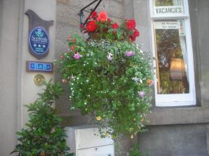una cesta colgada de flores al lado de un edificio en Sonas Guesthouse, en Edimburgo