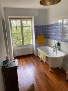 baño con bañera blanca y ventana en Le Jardin dans les vignes, en Barsac