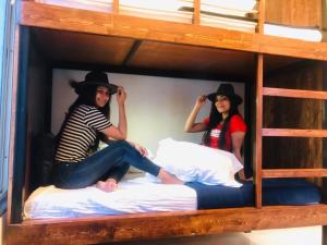 浦那的住宿－Jugglers Backpack，两人戴帽子,坐在双层床的床上