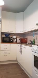 a white kitchen with white cabinets and appliances at Studio near City - Puinnintie in Pori