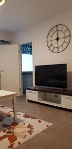 a living room with a large television and a clock on the wall at Studio near City - Puinnintie in Pori