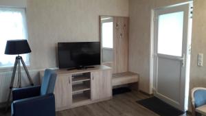 ein Wohnzimmer mit einem TV und einem blauen Stuhl in der Unterkunft Ferienhaus Jütte in Ebergötzen
