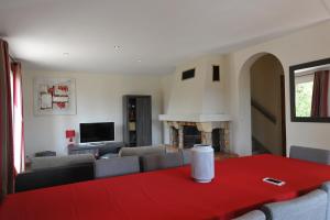 ein Wohnzimmer mit einem roten Tisch und einem Sofa in der Unterkunft La Villa des 3 ifs in Vallon-Pont-dʼArc