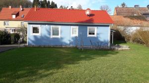 a blue house with a red roof on a yard at Ferienhaus Jütte in Ebergötzen