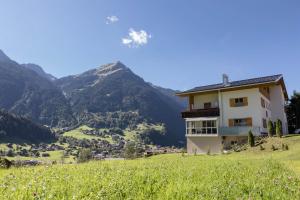 a house on a hill with mountains in the background at Gästehaus Laurin in Sankt Gallenkirch