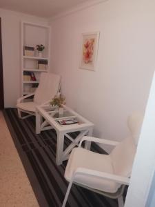 duas cadeiras brancas e uma mesa num quarto em Apartamento en Duplex em Jerez de la Frontera