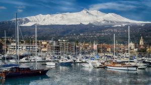 SiciliaEtnaMinio في ماسكالي: مجموعة من القوارب رست في ميناء مع جبل مغطى بالثلج