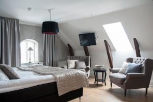 a bedroom with a bed and a chair and a tv at Hotell Slottsbacken in Visby