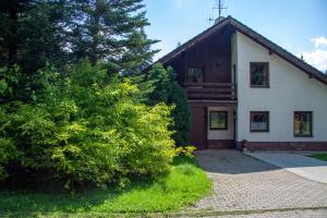 ein Haus mit einem Baum neben einer steinernen Einfahrt in der Unterkunft Apartmany Harrachov in Harrachov