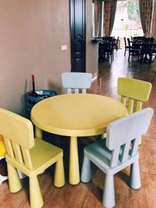 una mesa amarilla y 2 sillas con una mesa amarilla y 4 sillas en Amore Hotel, en Gudauta