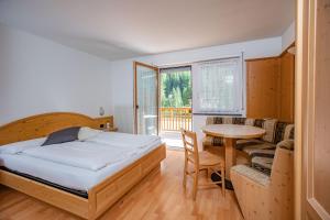 a bedroom with a bed and a table and a couch at Garnì Princess Apartments in Canazei
