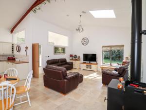 a living room with couches and a table and a kitchen at Thatchers Barn in Cheltenham