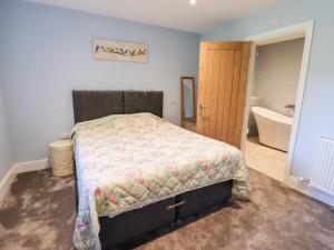 a bedroom with a bed and a bathroom with a tub at Thatchers Barn in Cheltenham