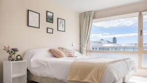 Dormitorio blanco con cama y ventana grande en Tu Apart en Bariloche 12 en San Carlos de Bariloche