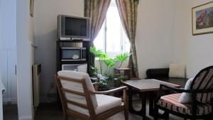 - un salon avec une télévision, une table et des chaises dans l'établissement Au Petit Hôtel, à Québec