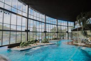 a large swimming pool in a building with windows at H2otel Congress & Medical SPA in Unhais da Serra