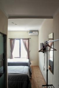 a small room with two beds and a window at bumimakhraja syariah 4 in Bandung