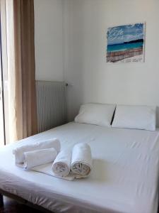Una cama blanca con toallas encima. en Nikolaos Residence, en Kiato