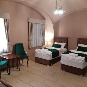 a hotel room with two beds and a table and chairs at Régi Posta Étterem és Fogadó in Debrecen