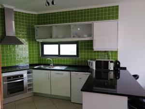 een groene betegelde keuken met witte kasten en een wastafel bij Vilas Horizonte in Porto Santo