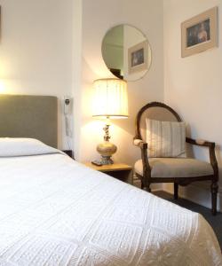 a bedroom with a bed and a chair and a mirror at Au Petit Hôtel in Quebec City