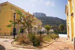 a yellow building with a mountain in the background at Casa Montesol in Calpe