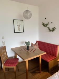 uma mesa de jantar e 2 cadeiras com almofadas vermelhas em Goisererglück em Bad Goisern