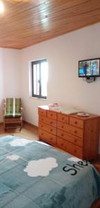 a bedroom with a bed and a dresser with a tv on the wall at Pêssego - AL in Arouca
