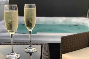 dos copas de champán sentadas en una mesa junto a una piscina en The Warren, en South Cerney