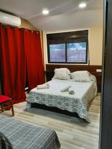1 dormitorio con 1 cama y cortinas rojas en Hostal Escarla, en Aren