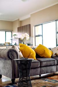 a living room with a couch with yellow pillows at Valleyside Executive Apartments in Ezulwini