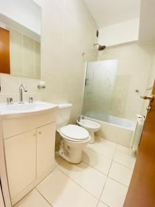 a white bathroom with a toilet and a sink at Departamento moderno pleno centro salta capital in Salta