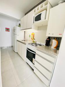 a kitchen with white cabinets and a stove and refrigerator at Departamento moderno pleno centro salta capital in Salta