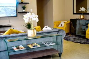 a living room with a blue couch and yellow chairs at Valleyside Executive Apartments in Ezulwini