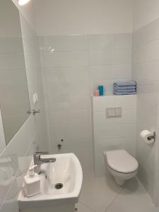 a white bathroom with a toilet and a sink at Apartament BLUE in Poznań