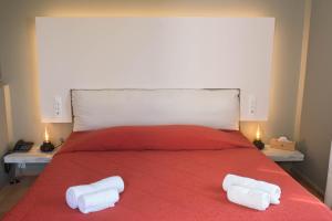 a bedroom with a red bed with two white towels on it at Mounda Beach Hotel in Skala Kefalonias