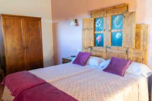 a bedroom with a large bed with purple pillows at Casa Rural Bonal in La Mata de los Olmos