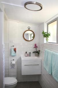 een witte badkamer met een toilet en een spiegel bij Courtyard Studio lights and wi fi during load shedding in Stellenbosch