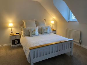 1 dormitorio con 1 cama blanca grande con almohadas en Arthur Street Guest Cottage (Sister cottage number 3), en Hillsborough