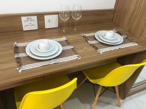 a table with yellow chairs and plates and wine glasses at Resort Granja Brasil Itaipava Piscinas aquecidas in Petrópolis