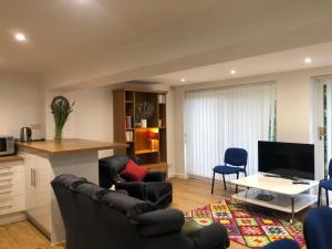 a living room with two chairs a table and a tv at The Game Keeper's Lodge in Welwyn