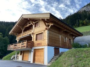 uma casa de madeira com uma varanda numa colina em Chalet Soleya em Le Grand-Bornand