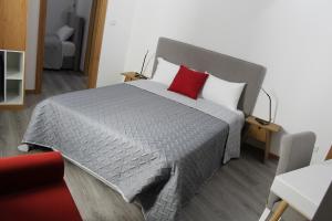 um quarto com uma cama grande e uma almofada vermelha em Alojamento Girassol em Castelo Branco