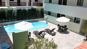 un patio avec des tables et des parasols et une piscine dans l'établissement PRAIA RESIDENCE 303A - Porto de Galinhas - PE, à Porto de Galinhas