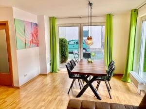ein Esszimmer mit grünen Vorhängen sowie einem Holztisch und Stühlen in der Unterkunft Elbflair in Pirna